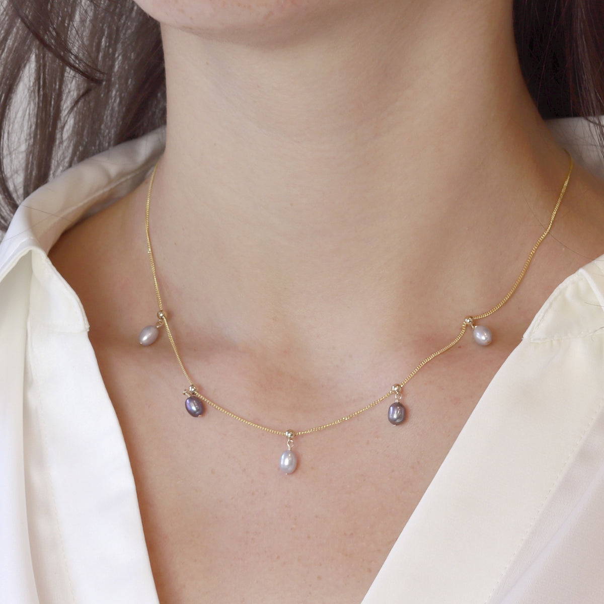Delicate adjustable pearl necklace worn by model, featuring elegant grey pearls for a refined look.