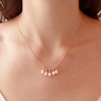 Model showcasing the delicate adjustable white pearl necklace, worn together with other accessories.