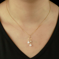 Elegant double drop pearl pendant in gold, showcased on a model for a stylish look.