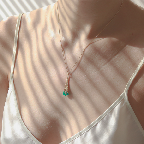 Elegant gold hammered textured triangle pendant with a vibrant green onyx gemstone, showcased on a model for a stylish and modern look.