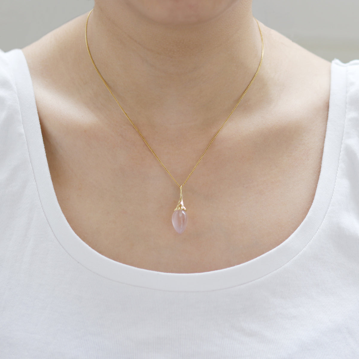 Elegant gold rose acorn pendant necklace, showcasing a luxurious design on the model.