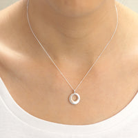 Sleek silver halo pendant with a shimmering gemstone, perfect for adding a touch of elegance to any outfit.