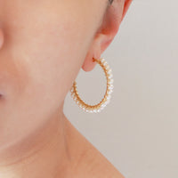Model wearing large hinged pearl hoop earrings showcasing a modern classic look.