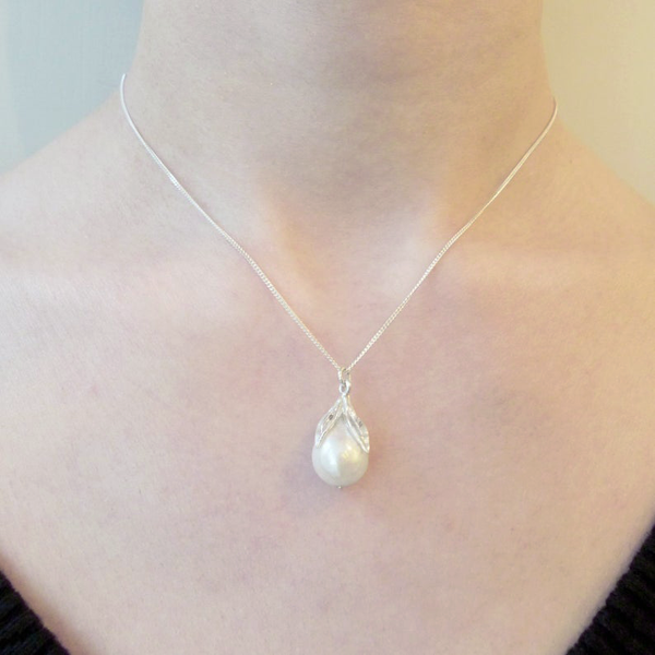 Elegant white pearl pendant with a silver leaf design, adding a touch of nature-inspired beauty.