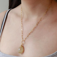 Model wearing a large pear-cut rutilated quartz necklace, showcasing its unique golden inclusions and elegant design.
